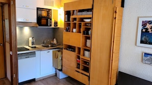 Une cuisine compacte équipée d’un four à micro-ondes, d’un évier et d’armoires de rangement en bois.