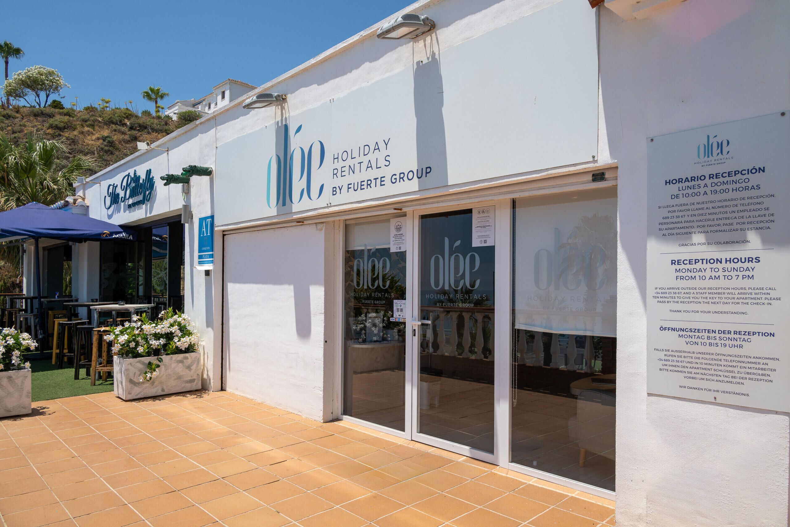 Un edificio con un cartello di 'Holiday Rentals by Fuerte Group' e una reception con porte in vetro.