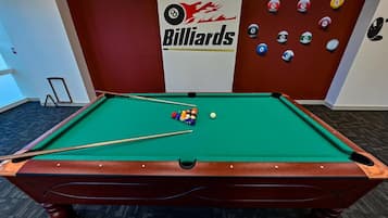 Ett biljardbord med bollar och köer, en biljardlogotyp och en vägg med numrerade bollar.