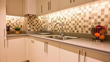 A modern kitchen with a checkered backsplash, stainless steel sink, and a fruit bowl on the counter.