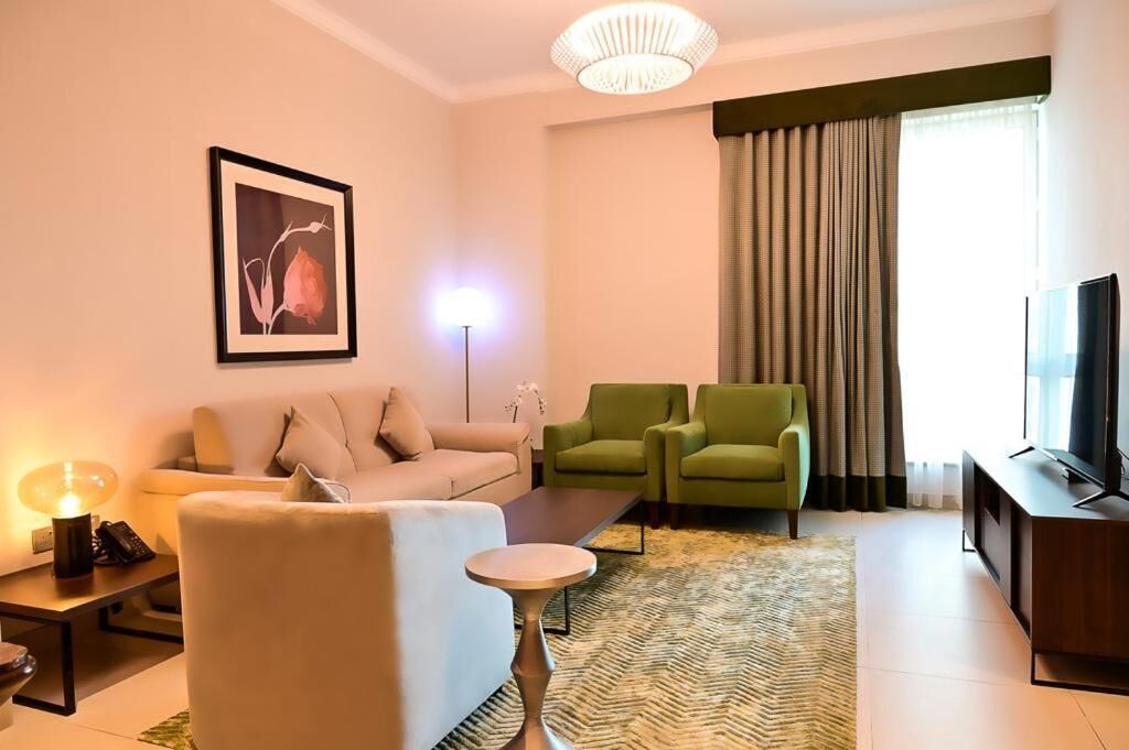 A modern living room with a sofa, two armchairs, a coffee table, a TV, and a framed picture on the wall.