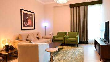A modern living room with a sofa, two armchairs, a coffee table, a TV, and a framed picture on the wall.
