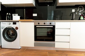 A compact kitchen with a built-in washer, oven, and a small countertop. - Gold Apartment Ferrel II (Ferrel)