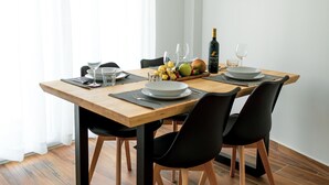Ein Essbereich mit einem Holztisch, gedeckt für zwei Personen, schwarzen Stühlen und einer Weinflasche.
