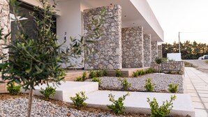 A modern building with stone pillars and a gravel pathway. - Pebble Garden (Kos)