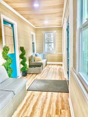 A cozy interior with a wooden floor, a grey sofa, a small table, and a window with a view. - 5 bedroom with parking for families and groups. (Springfield)