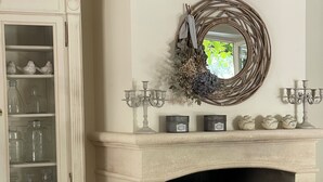 A living room with a fireplace, a cabinet with glass doors, a wicker basket, and a glass table.
