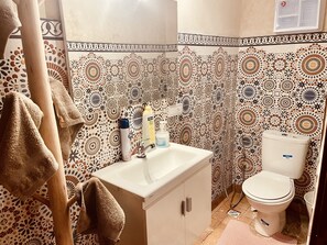 Une salle de bain avec des carreaux décorés, un lavabo, des toilettes et des serviettes.