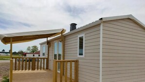 A small, single-story mobile home with a wooden deck and a covered porch. - Mobile Home 6 Domaine DE LA Grange DES Champs (Lorris)