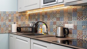 A modern kitchen with white cabinets, a microwave, and a patterned backsplash. - Hostel JessApart - Aleje Jerozolimskie (Warsaw)