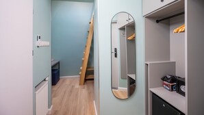 A narrow hallway with a wooden ladder leading to a staircase, a mirror, and a wardrobe with hanging clothes. - Hostel JessApart - Aleje Jerozolimskie (Warsaw)