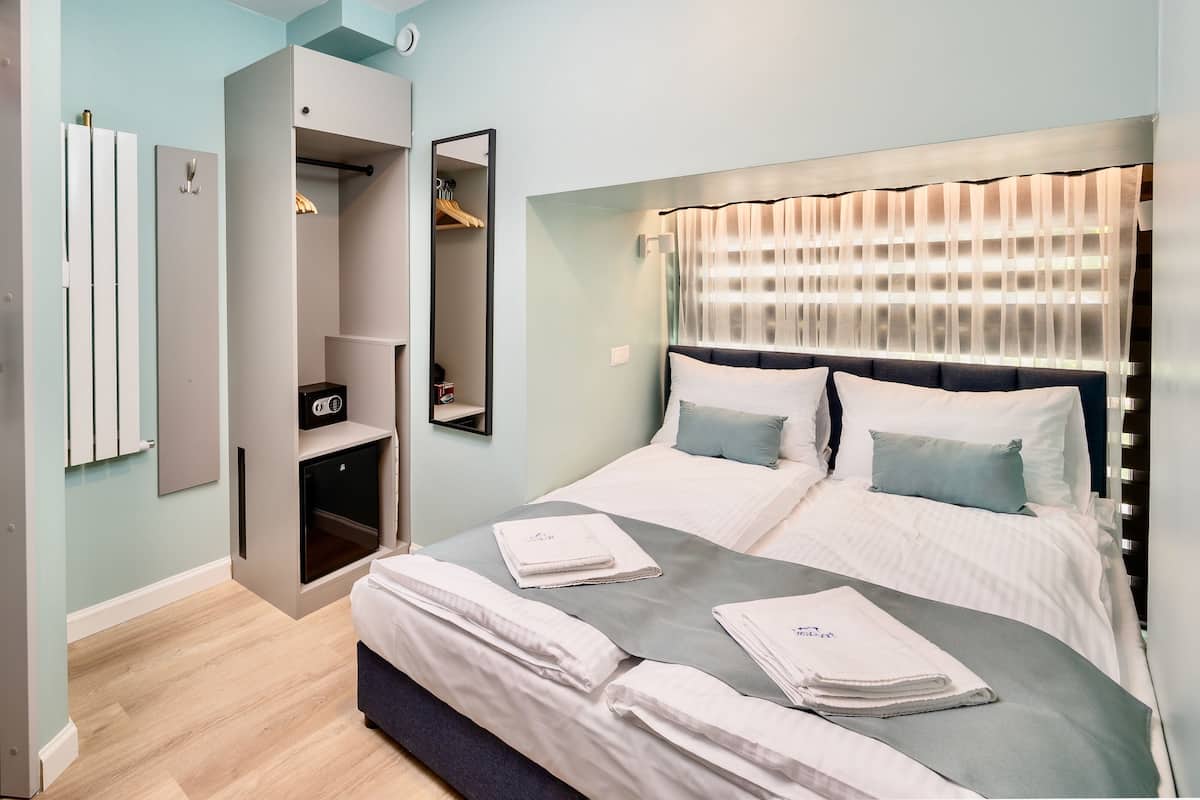 A modern bedroom with a large bed, a built-in wardrobe, and a mirror.