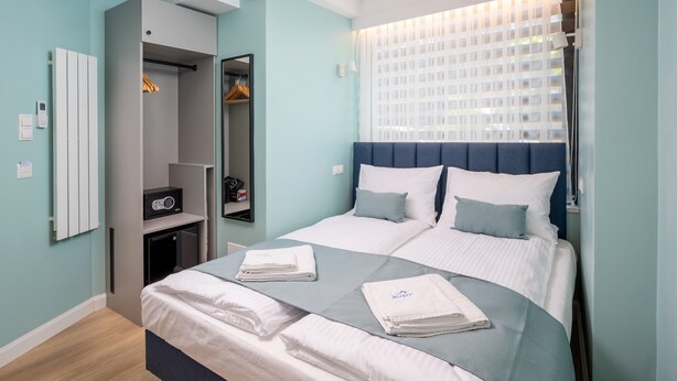 A modern bedroom with a bed, a wardrobe, and a mirror. - Hostel JessApart - Aleje Jerozolimskie (Warsaw)
