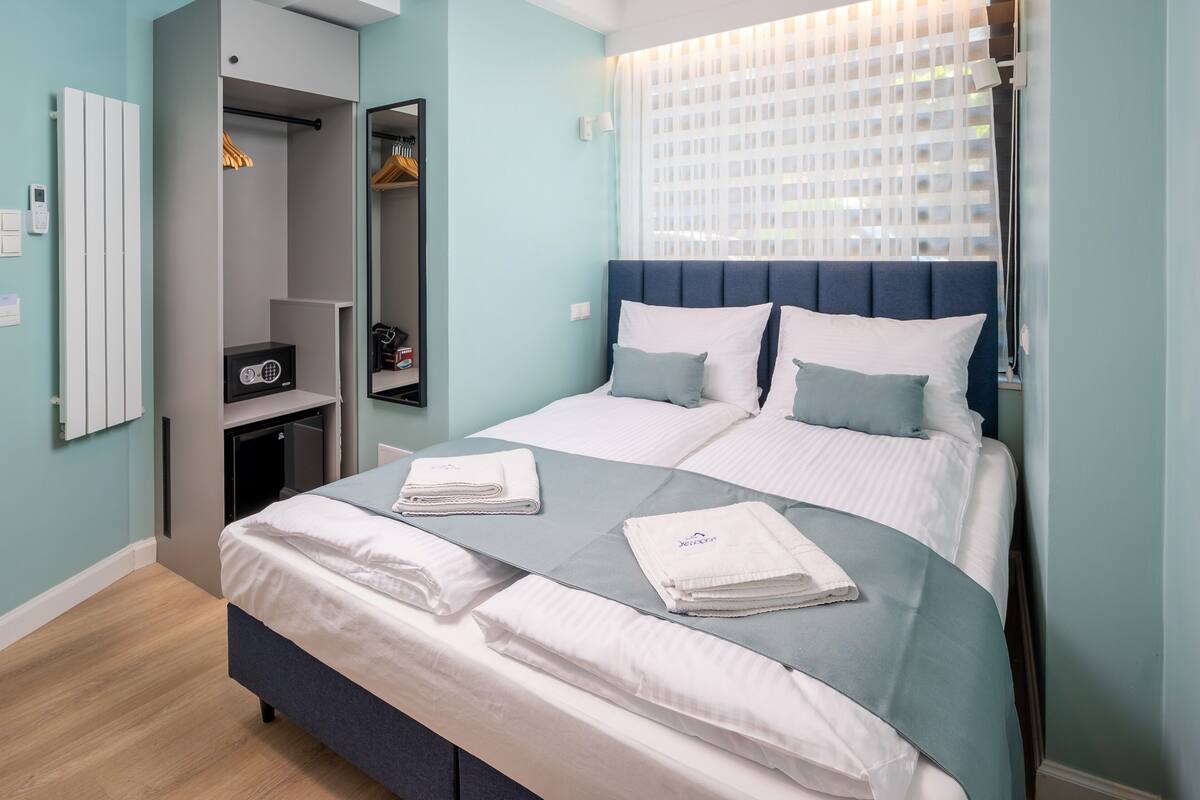 A modern bedroom with a bed, a wardrobe, and a mirror.