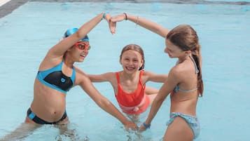 Piscina com três pessoas formando um coração na água.