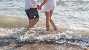 A couple holding hands on a beach with ocean waves. - Luxury Premium Finese Hotel & SPA (Golem)