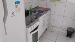 Une cuisine compacte équipée d’un réfrig érateur, d’une cuisinière, d’un évier et d’un petit tabouret.