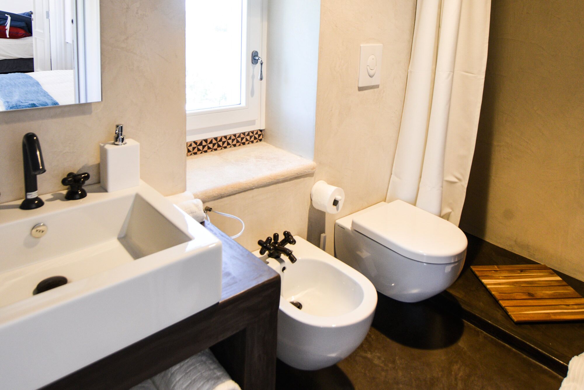 Une salle de bain équipée d’un lavabo, d’un bidet, de toilettes et d’un miroir.