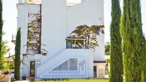 A modern building with a prominent staircase leading to the entrance, surrounded by tall cypress trees. - Masseria Torrechiara Eco Dimora di Charme. (Corato)