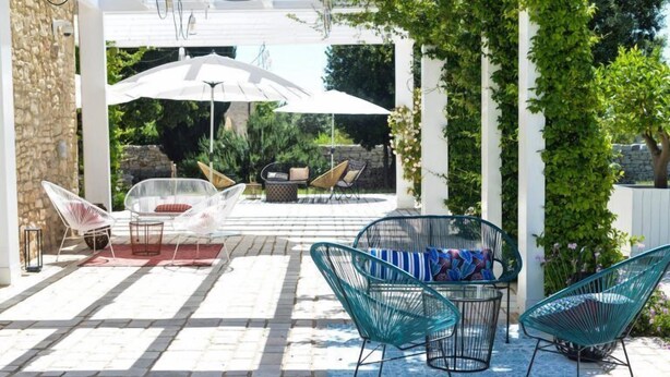 An outdoor patio with a stone floor, white pergola, and various seating options including chairs and a table. - Masseria Torrechiara Eco Dimora di Charme. (Corato)