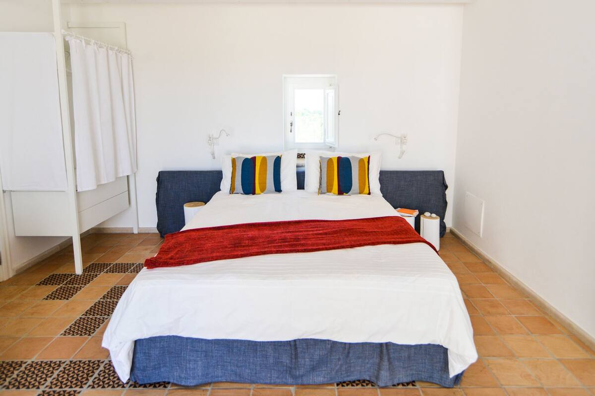 A bedroom with a bed, a window, and a door.