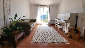 Ein gemütliches Wohnzimmer mit einem Klavier, einem Sofa, einem Teppich und einer Gitarre.