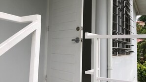 Une porte blanche portant le numéro 18, un sol carrelé et une balustrade de balcon.