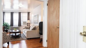A living room with a sofa, armchair, coffee table, and a wooden door. - Bryn Mawr Has It All (Bryn Mawr)