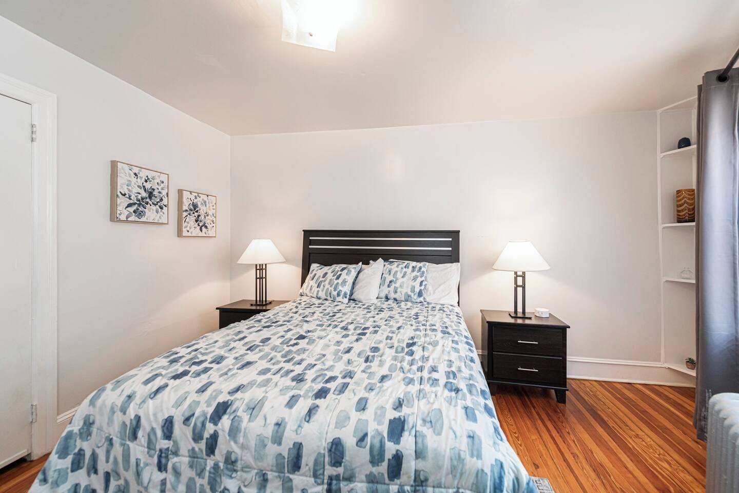 Una camera da letto con un letto, due comodini, due lampade, un piccolo tavolo e una mensola a parete.