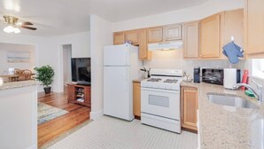 A modern kitchen with wooden cabinets, a white refrigerator, a stove, and a sink.
