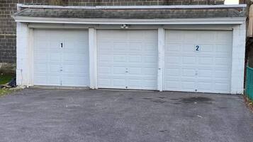 Un garage con tre porte numerate, un muro in mattoni e un albero.