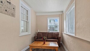 A cozy living room with a brown leather sofa, a wooden coffee table, and a vase with flowers. - Stay At Our Tasteful, Private, & Elegant Abode (Devon)