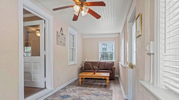 A hallway with a ceiling fan, a brown sofa, a wooden coffee table, and a patterned rug. - Stay At Our Tasteful, Private, & Elegant Abode (Devon)