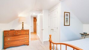 Quarto com cômoda de madeira, cama e ventilador de teto.