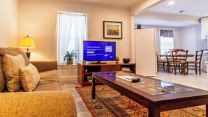 A living room with a sofa, a coffee table, a television, and a dining area with chairs and a table. - Devon - Horse Show, History, Walk to Shops, Café's (Devon)