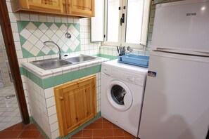 Eine kleine Küche mit Spüle, Waschmaschine und Kühlschrank.