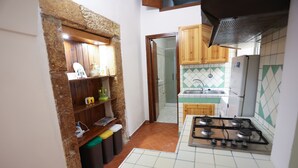 Une cuisine de taille réduite, dotée d’une cuisinière à gaz, de meubles en bois et d’un dosseret carrelé.