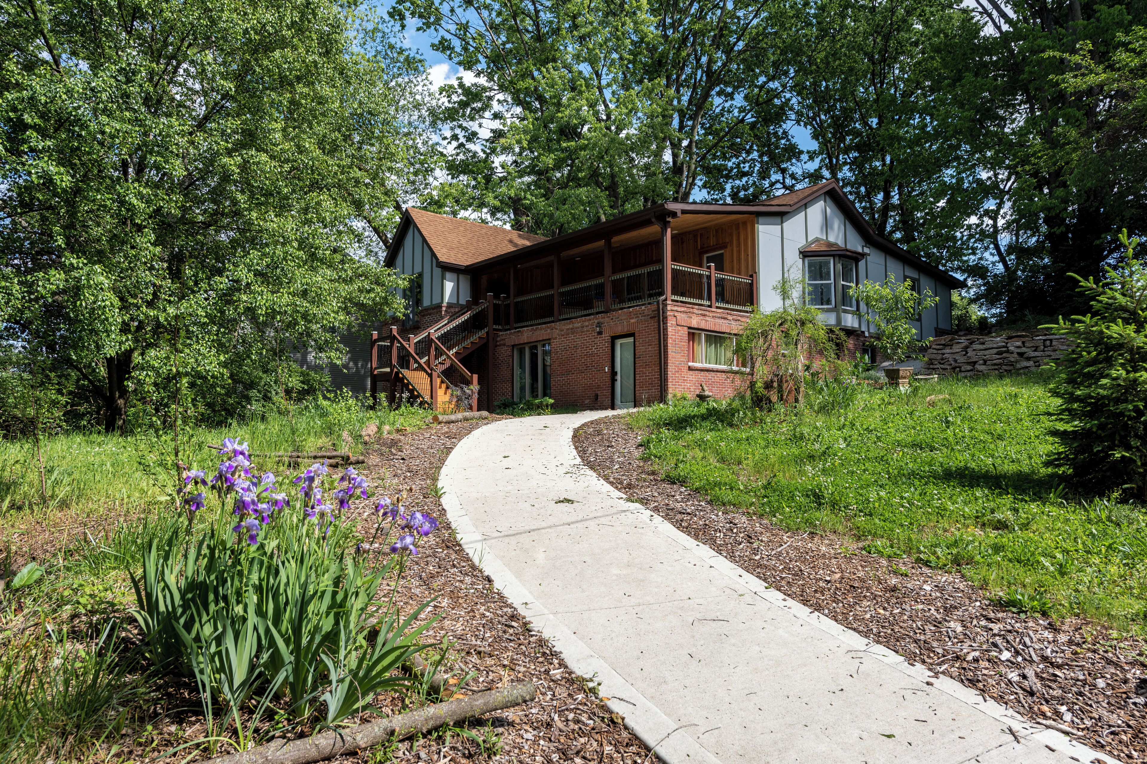 A two-story house with a porch and a stone wall.