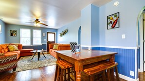 Un salon avec une table à manger en bois, un canapé orange et un ventilateur de plafond.