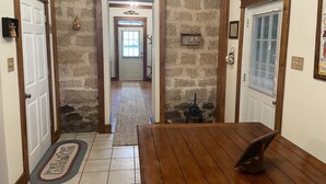 A hallway with a wooden table, a rug, and a stone wall. - Whole House Rental - Private Cottage near Historic Hermann, Missouri (Hermann)