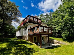 A two-story house with a balcony, surrounded by lush greenery. - Colby Cottage in Taylors Falls, 4 Bedroom Home - Walk to Interstate Park (Taylors Falls)