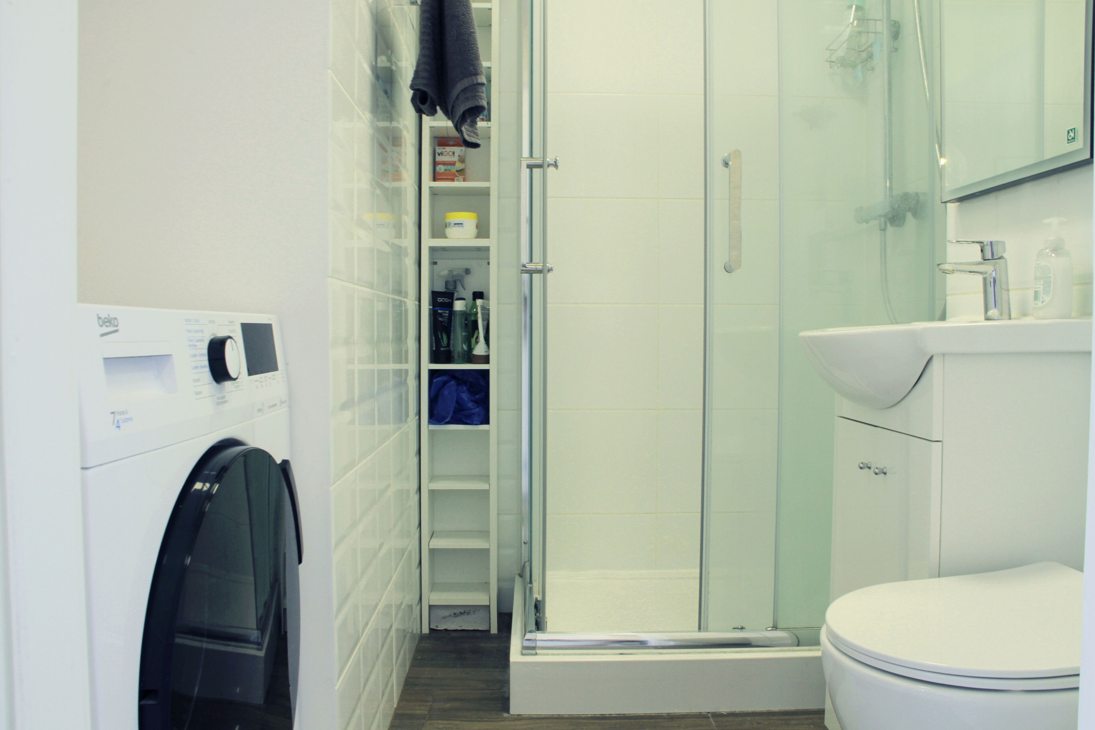 Een moderne badkamer met een douche met glazen wand, een wit toilet en een ingebouwd wastafel.
