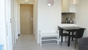 A modern kitchen with a dining table, chairs, a clock, and a fan. - Central New Flat. AC, Park View , 2 Rooms (Warszawa)