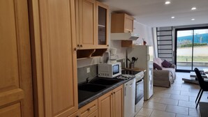 Una cocina moderna con armarios de madera, microondas integrado y cafetera.