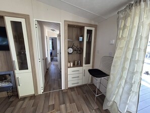 Ein Zimmer mit Küchenzeile, einem Essbereich mit einem Stuhl und einem durch eine offene Tür einsehbaren Badezimmer.