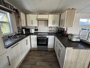 A compact kitchen with white cabinets, a stainless steel stove, and a coffee maker. - NV 1242 - Beach Resort Nieuwvliet-Bad (Nieuwvliet)