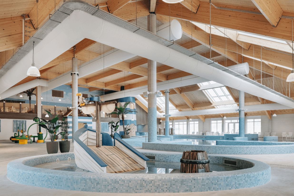 A spacious indoor swimming pool area with multiple levels and a central slide.