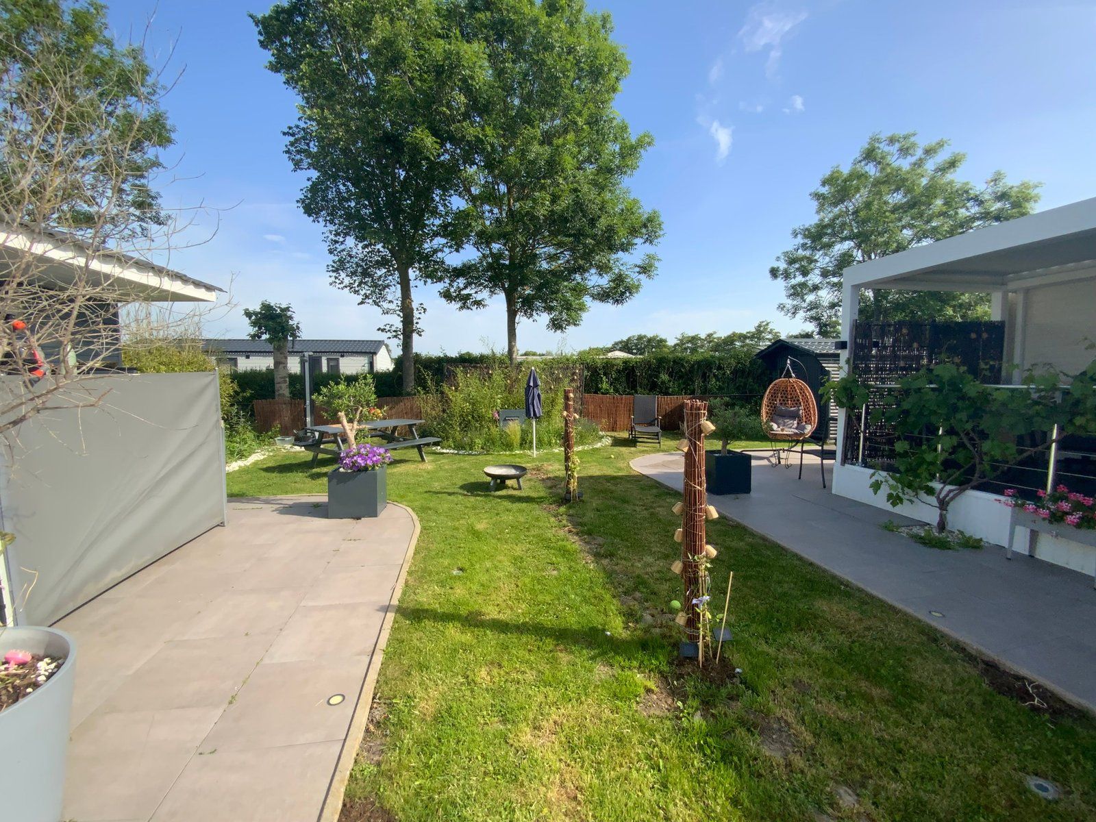 A backyard with a picnic table, a hanging chair, and a small garden area.