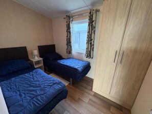 A bedroom with two beds, a wardrobe, a nightstand, and a window with curtains. - NV 1242 - Beach Resort Nieuwvliet-Bad (Nieuwvliet)