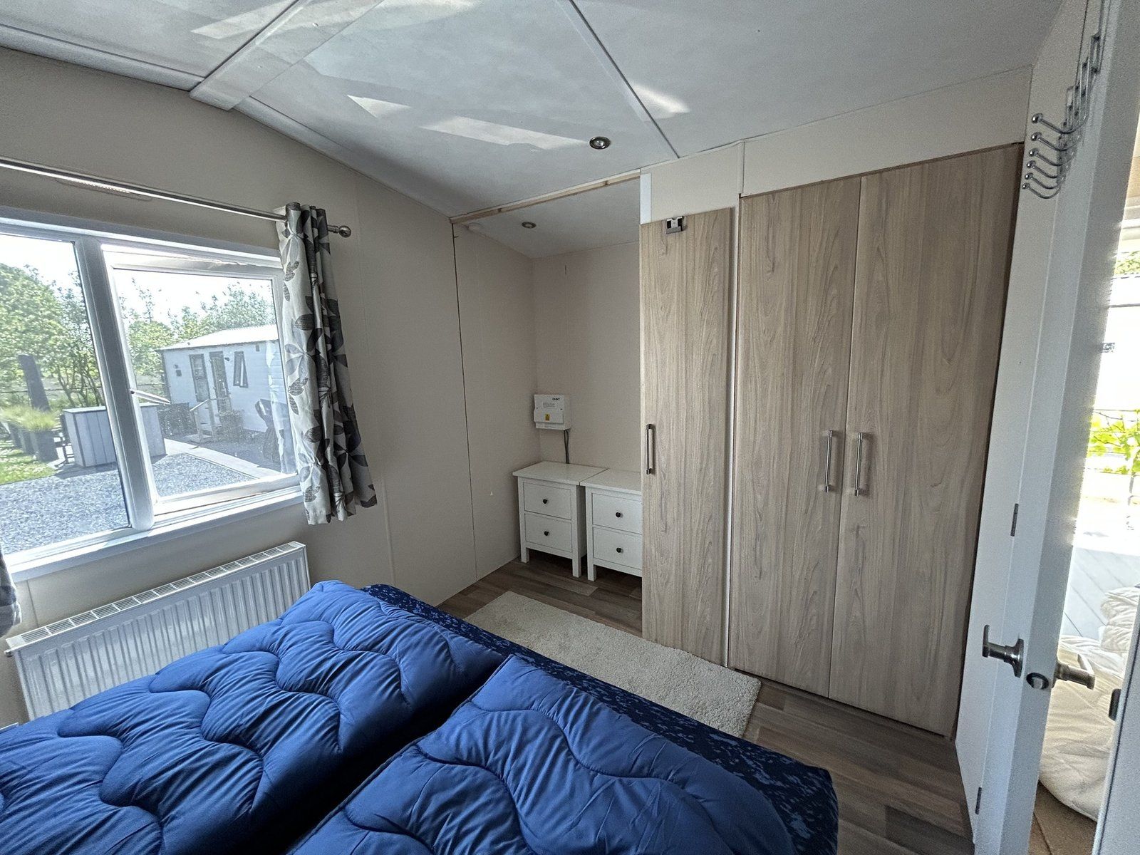 A bedroom with a bed, a dresser, a wardrobe, and a window.